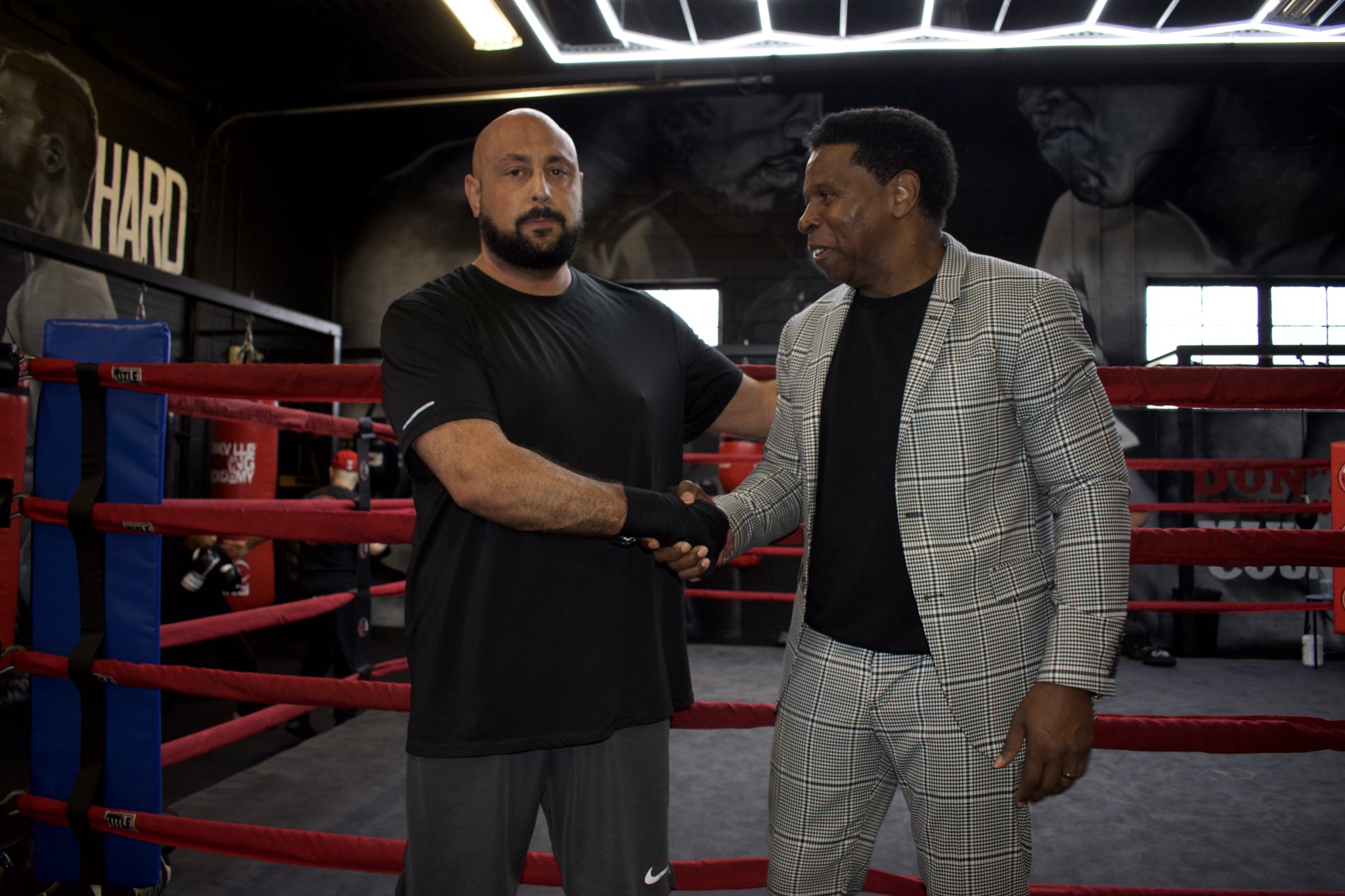 Tony De Pasquale shaking hands with Michael Pinball Clemons in a boxing gym